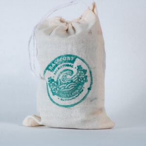 A canvas drawstring bag with a green Lax Wax base coat logo sits against a white background, showing the gathered top and natural cotton fabric texture.